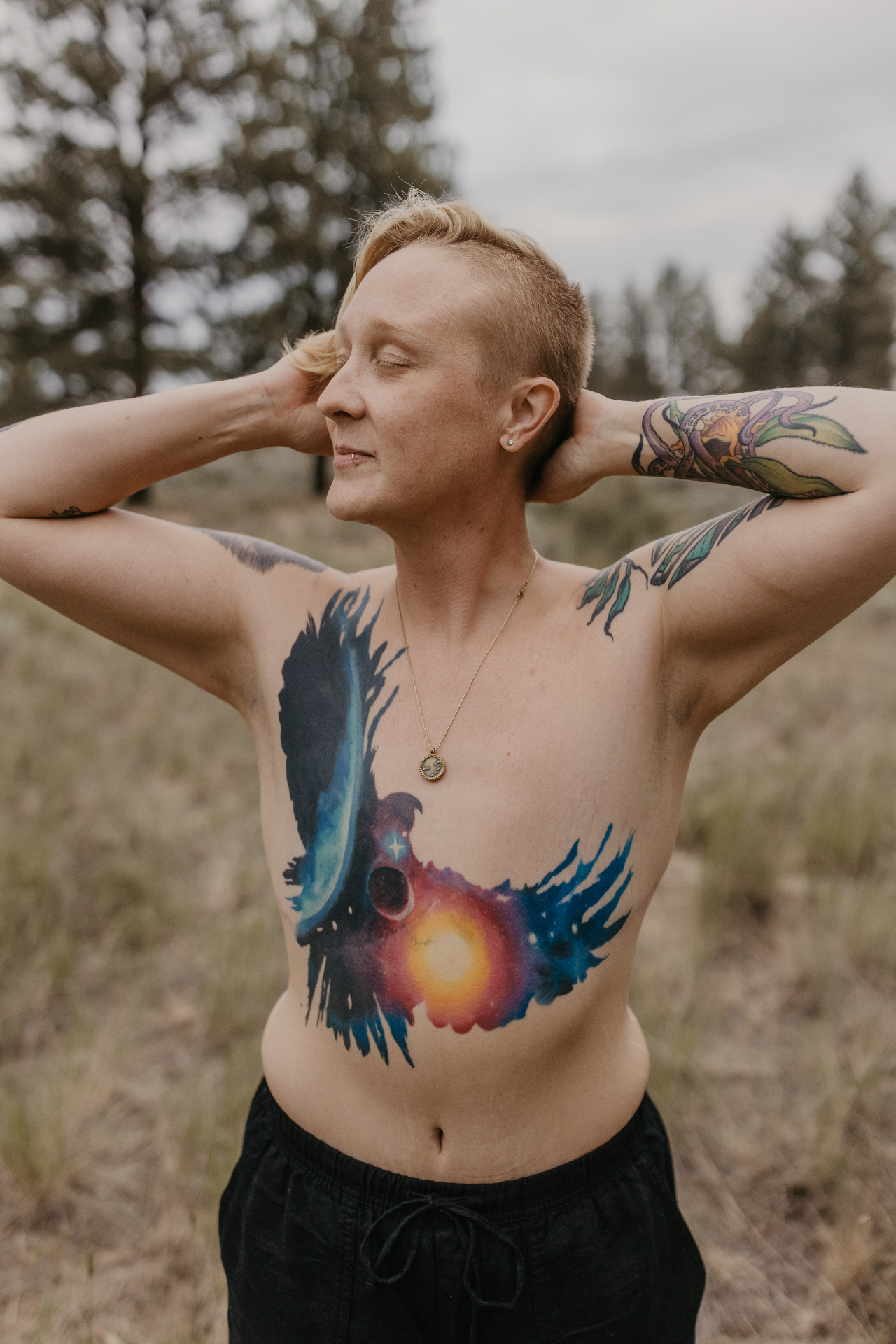 Jules Marsh standing in an open meadow among pines, hands resting behind her head